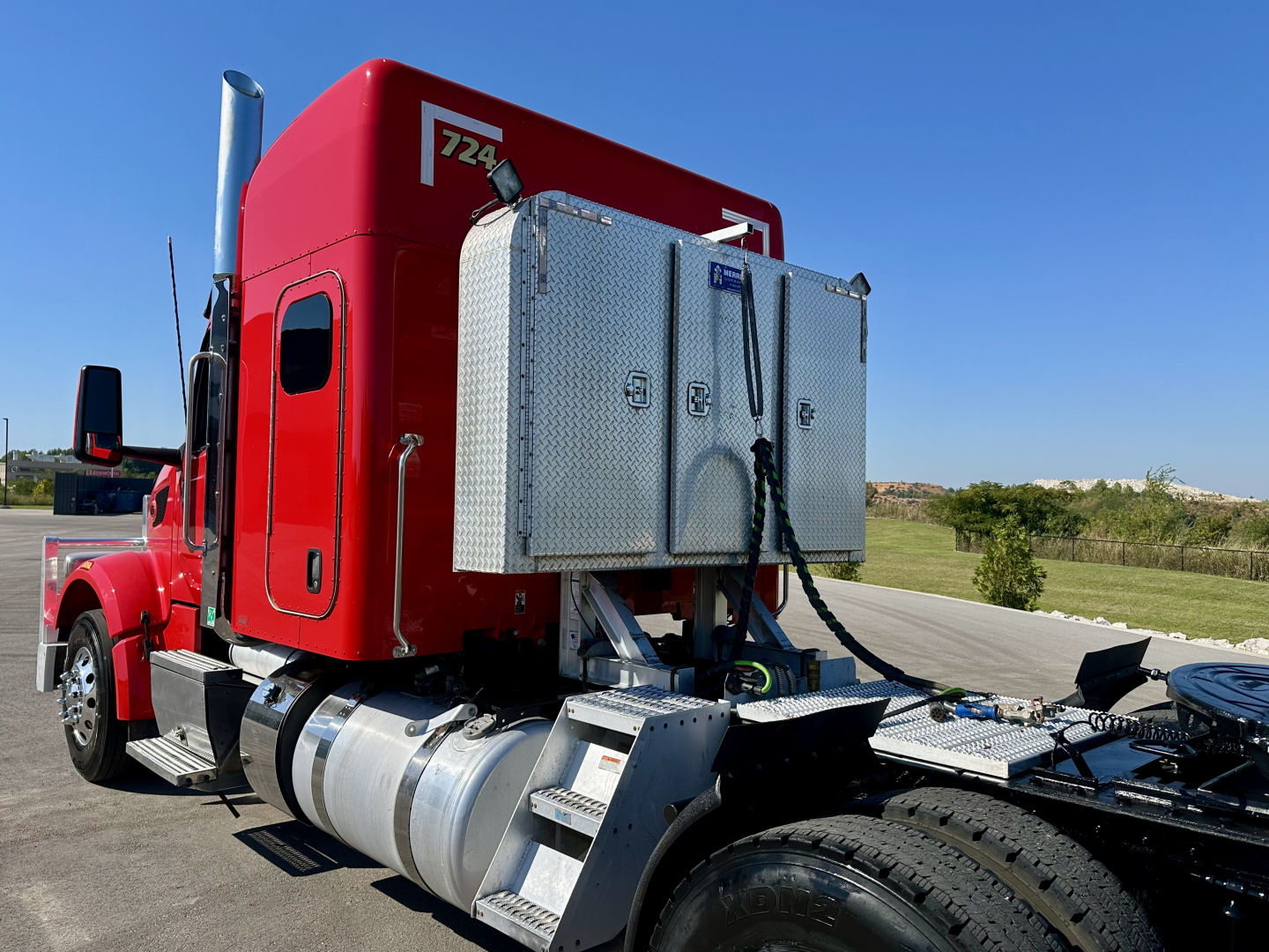 Peterbilt 567 truck cab rear with fuel tanks and diamond-plate toolbox, red sleeper cab, chrome exhaust stack, chassis side view.