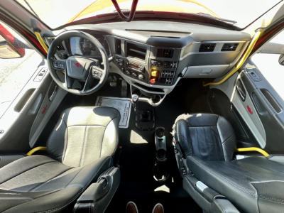 Peterbilt 567 cab interior view showing steering wheel, instrument cluster, center console, and two seats.