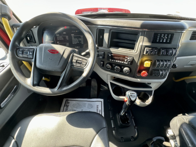 Peterbilt 567 cockpit showing steering wheel and dashboard with gear shifter and control panel.