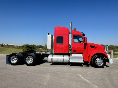 Peterbilt 567 sleeper cab truck side view showing red cab and chrome fuel tanks with dual rear axles