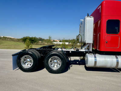 Peterbilt 567 tractor truck chassis showing dual rear axles and fuel tanks with red sleeper cab.