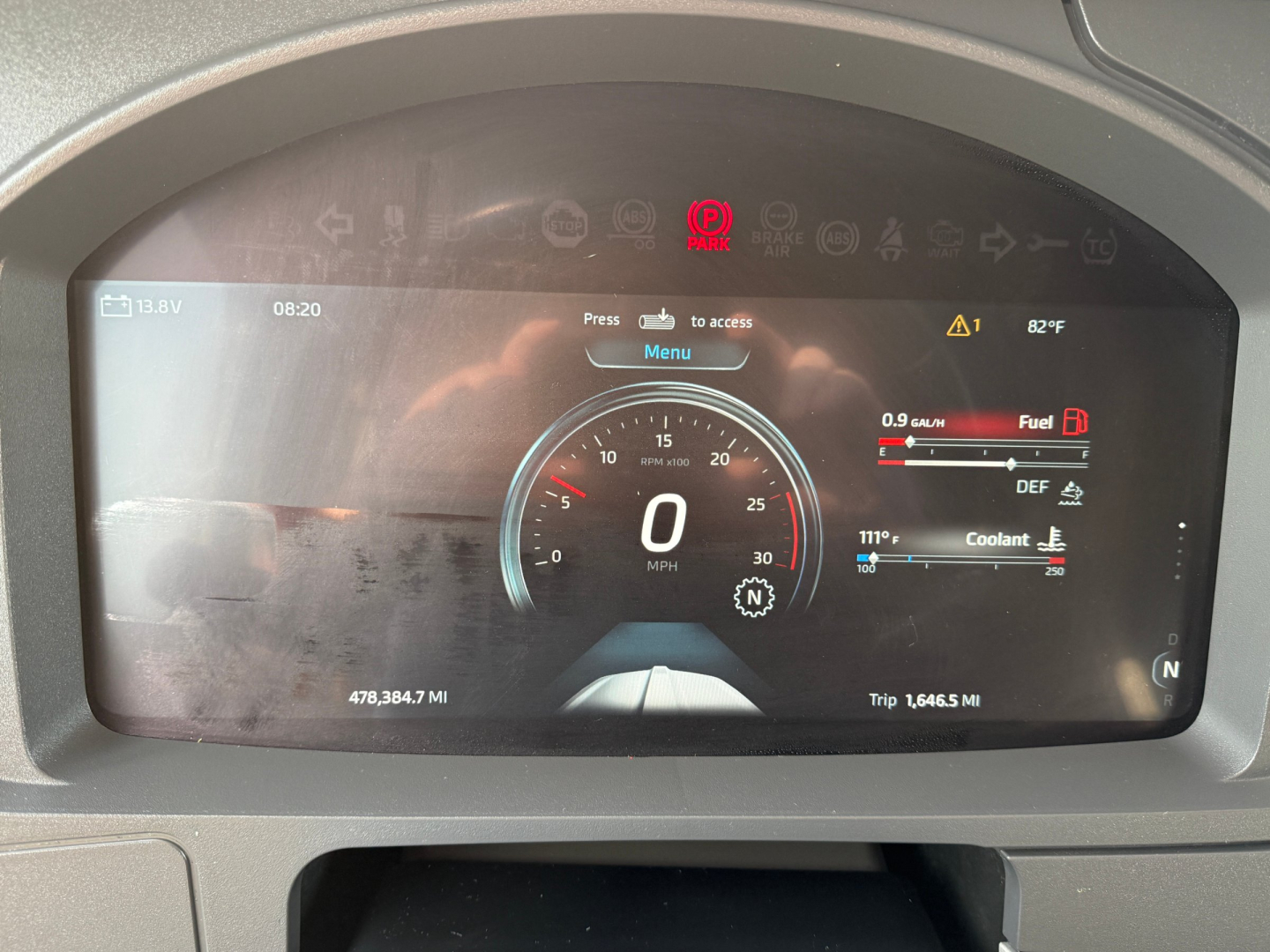 Dash display of 2023 Kenworth T680 with digital instrument cluster showing speed 0 MPH, trip data, fuel, DEF, coolant gauges.