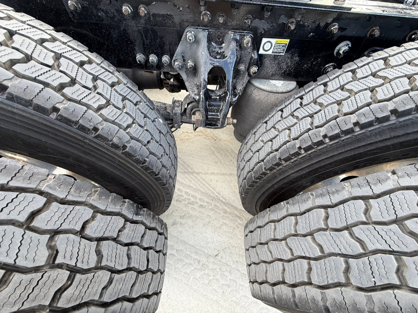 Kenworth truck undercarriage showing dual rear axles and tire treads with suspension components visible.