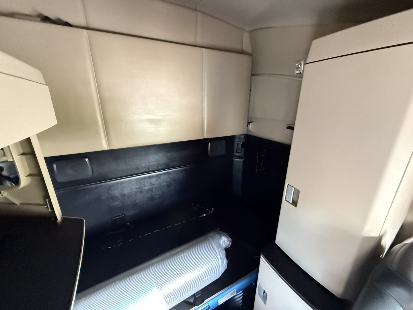Kenworth T680 sleeper cab interior cargo area with beige upholstery and storage compartments in view.