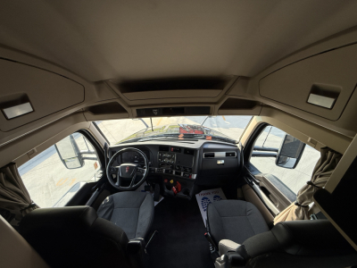 Kenworth T680 truck cab interior view from front seat area showing steering wheel, dashboard, and seats.