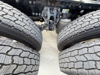 Kenworth truck undercarriage showing dual rear axles and tire treads with suspension components visible.
