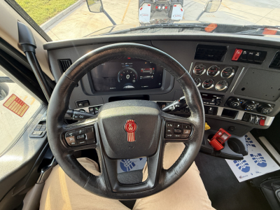 Kenworth T680 steering wheel and dashboard interior with analog gauges and control switches.