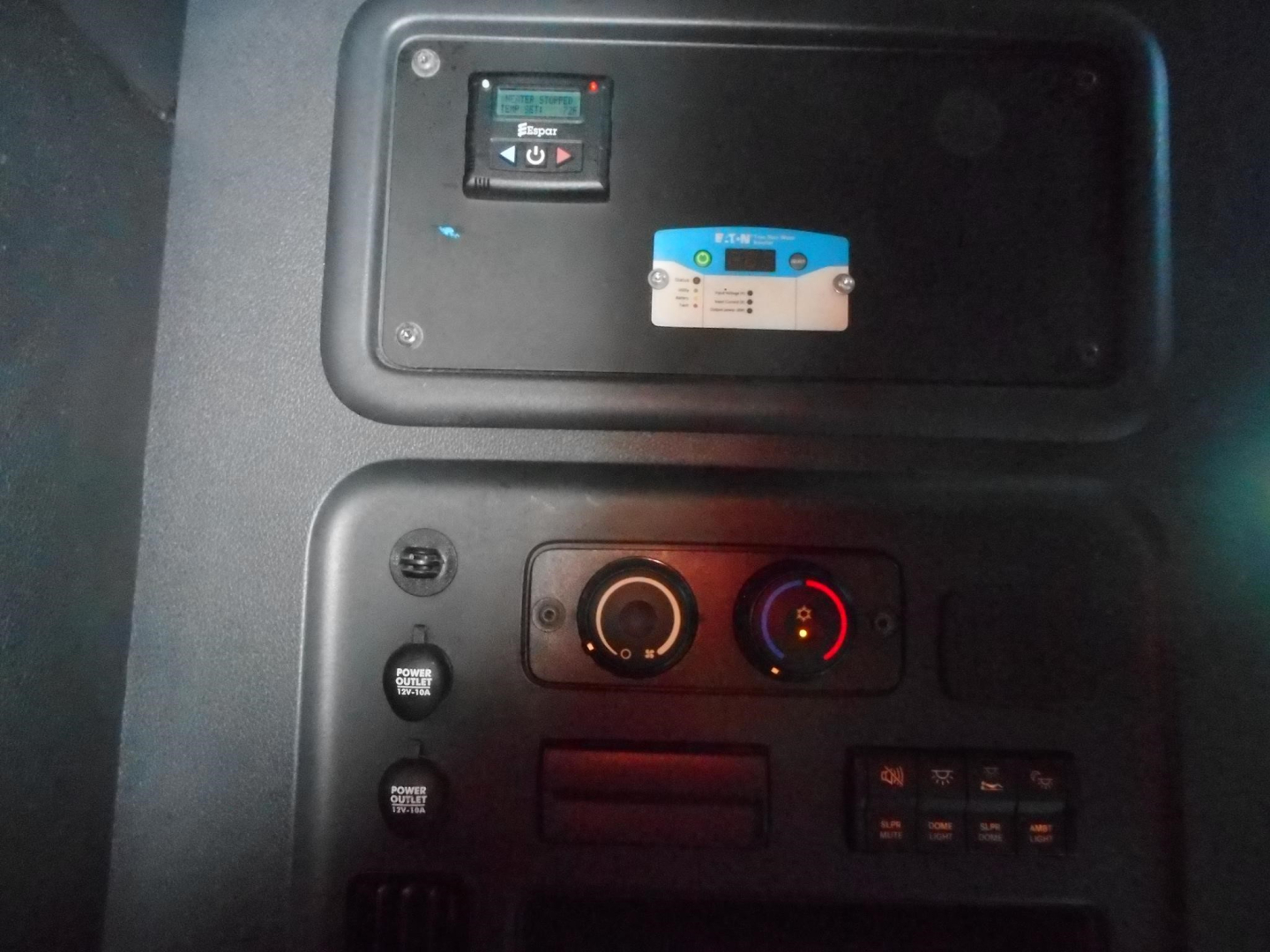 Cab controls panel of a Freightliner Cascadia showing ignition switch, climate controls, and auxiliary switches.