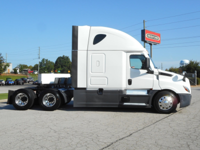 Truck side view of a 2024 Freightliner Cascadia 126 conventional sleeper with white cab, black accents, chrome wheels, and tandem rear axles.