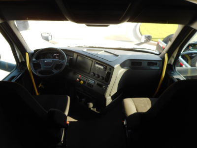 Truck cab interior dashboard view from driver seat showing steering wheel, dashboard console, and seating.