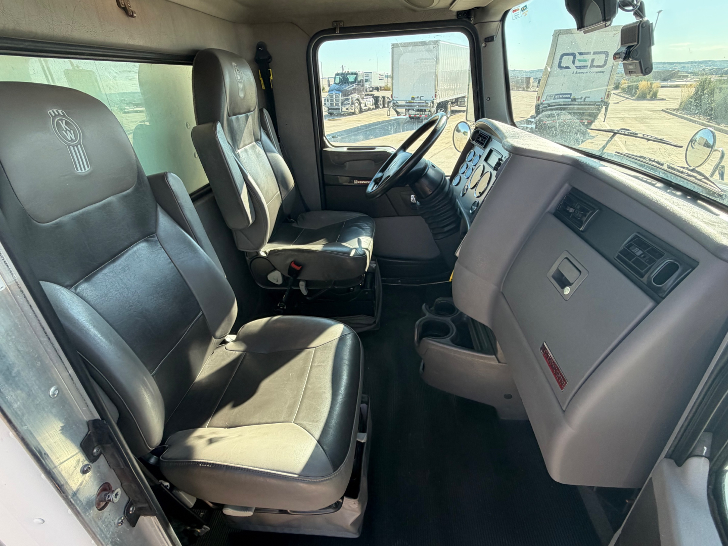 Cab interior of a 2020 Kenworth T270 with driver and passenger seats, steering wheel, dashboard, and center console visible.
