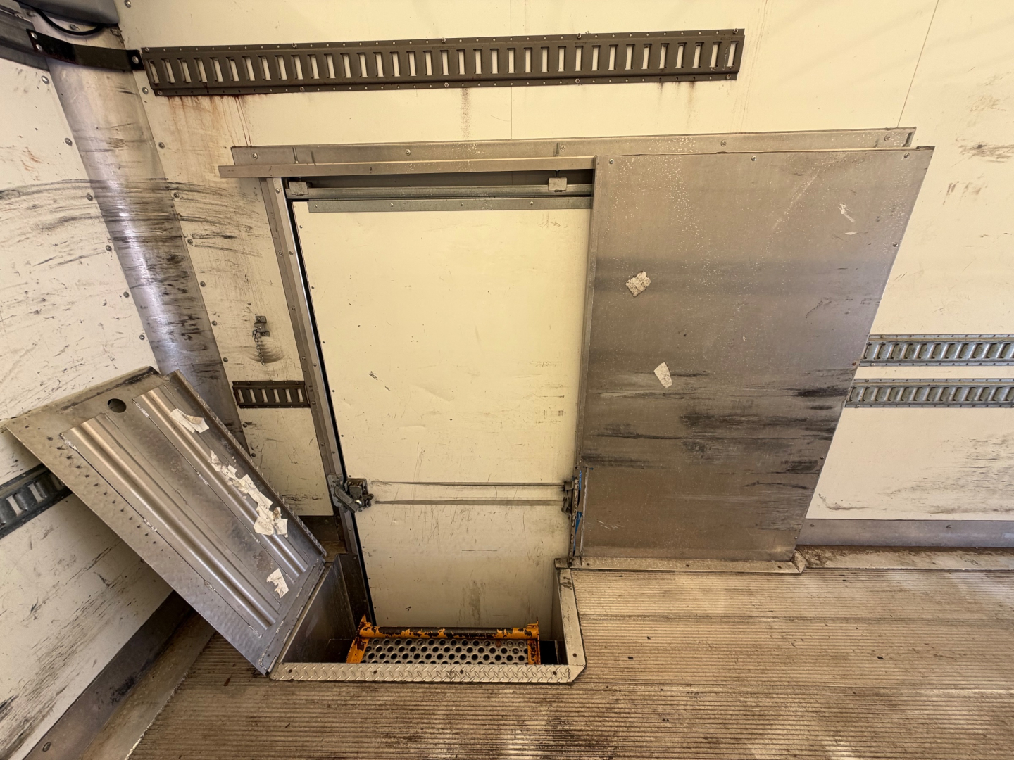 Kenworth T270 truck cargo area with side access hatch and metal panels, interior floor visible, some equipment/rails along walls.
