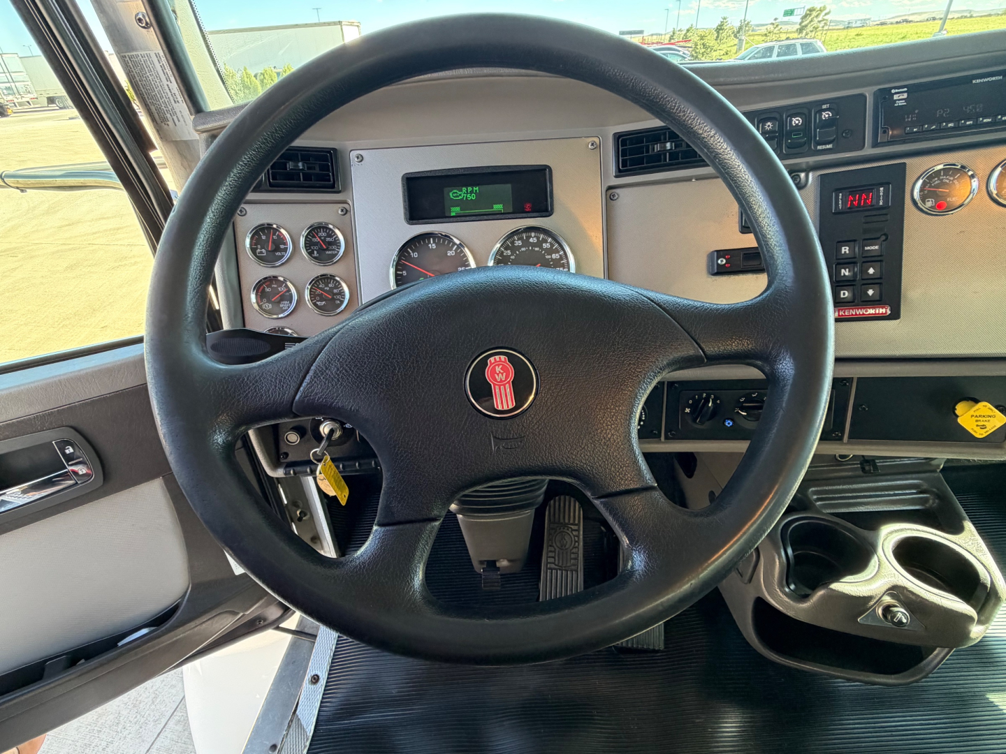 Dashboard and steering wheel of a Kenworth T270 truck showing instrument gauges, steering wheel with Kenworth emblem, ignition with key, and dashboard panels.