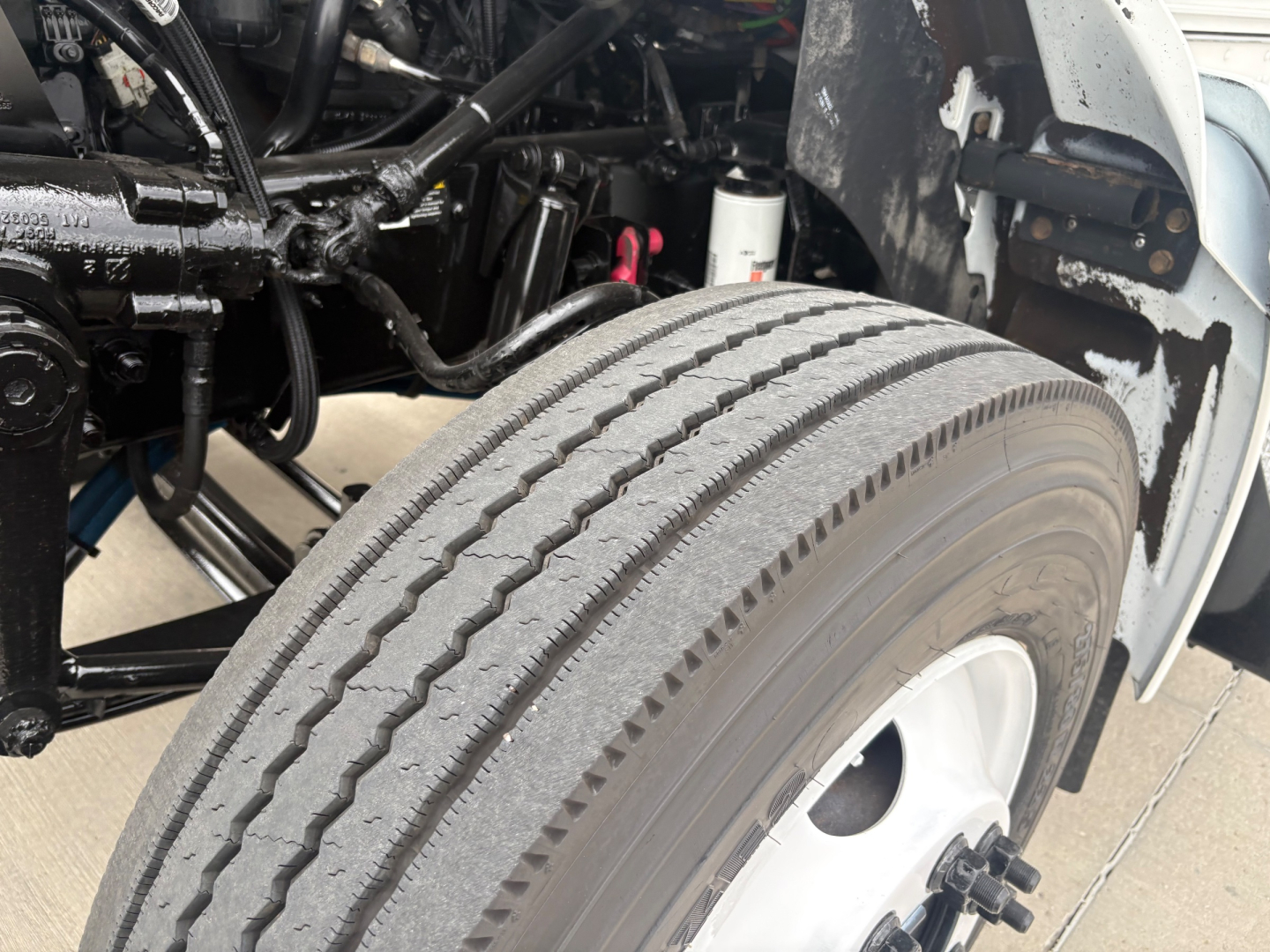 Kenworth T270 front wheel area showing steering chassis, tire tread, and under-hood components with exposed suspension lines.