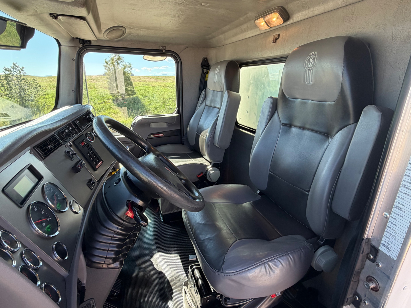 Interior of a Kenworth T270 cab showing steering wheel, dashboard gauges, and two black leather seats.
