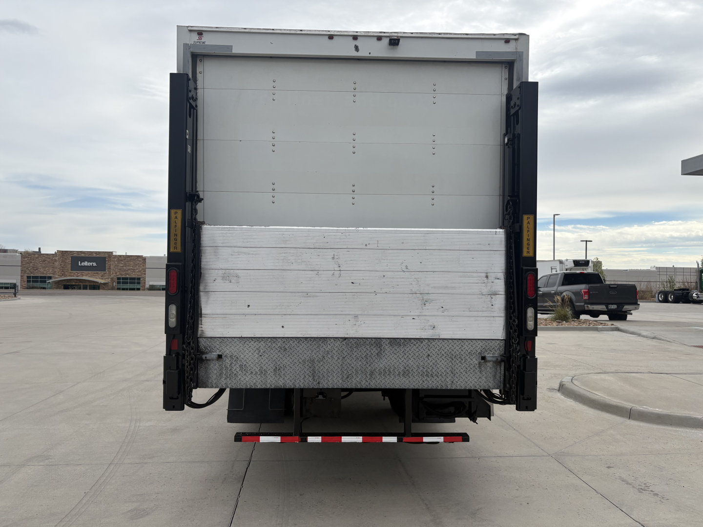 Truck rear view showing cargo box with metal tailgate and bumper, Kenworth T270, with reflective rear underride guard and payload space.