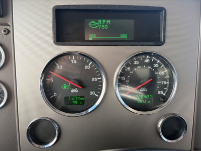 Kenworth dashboard showing RPM gauge, speedometer, and digital readouts; RPM 750 on screen with green bar, odometer 7124.9 miles, engine data and fuel