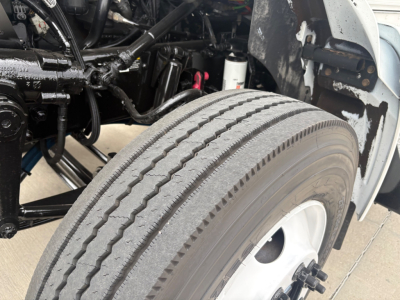 Kenworth T270 front wheel area showing steering chassis, tire tread, and under-hood components with exposed suspension lines.