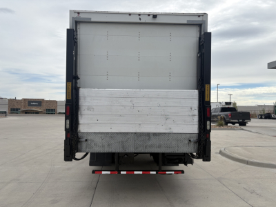 Truck rear view showing cargo box with metal tailgate and bumper, Kenworth T270, with reflective rear underride guard and payload space.