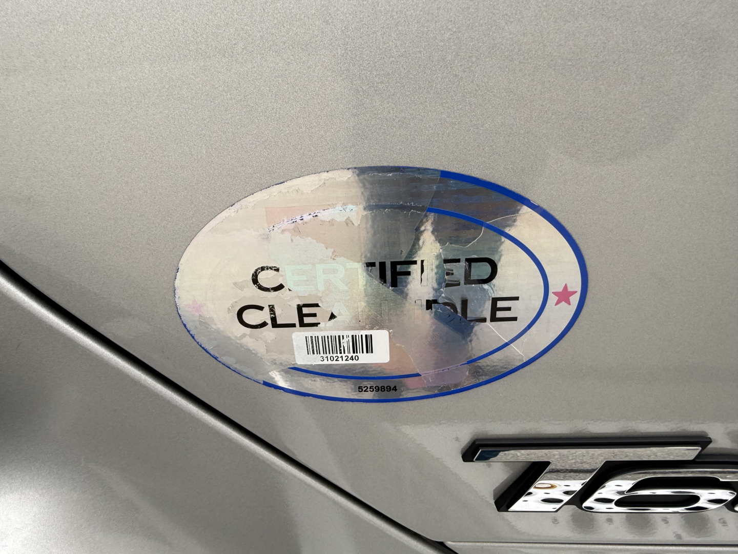 Kenworth T680 badge with a certified clean title sticker on silver truck body.