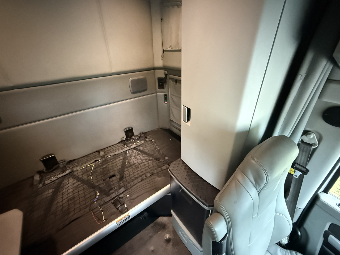 Interior of Kenworth T680 cab showing wiring and flooring beneath seat area.