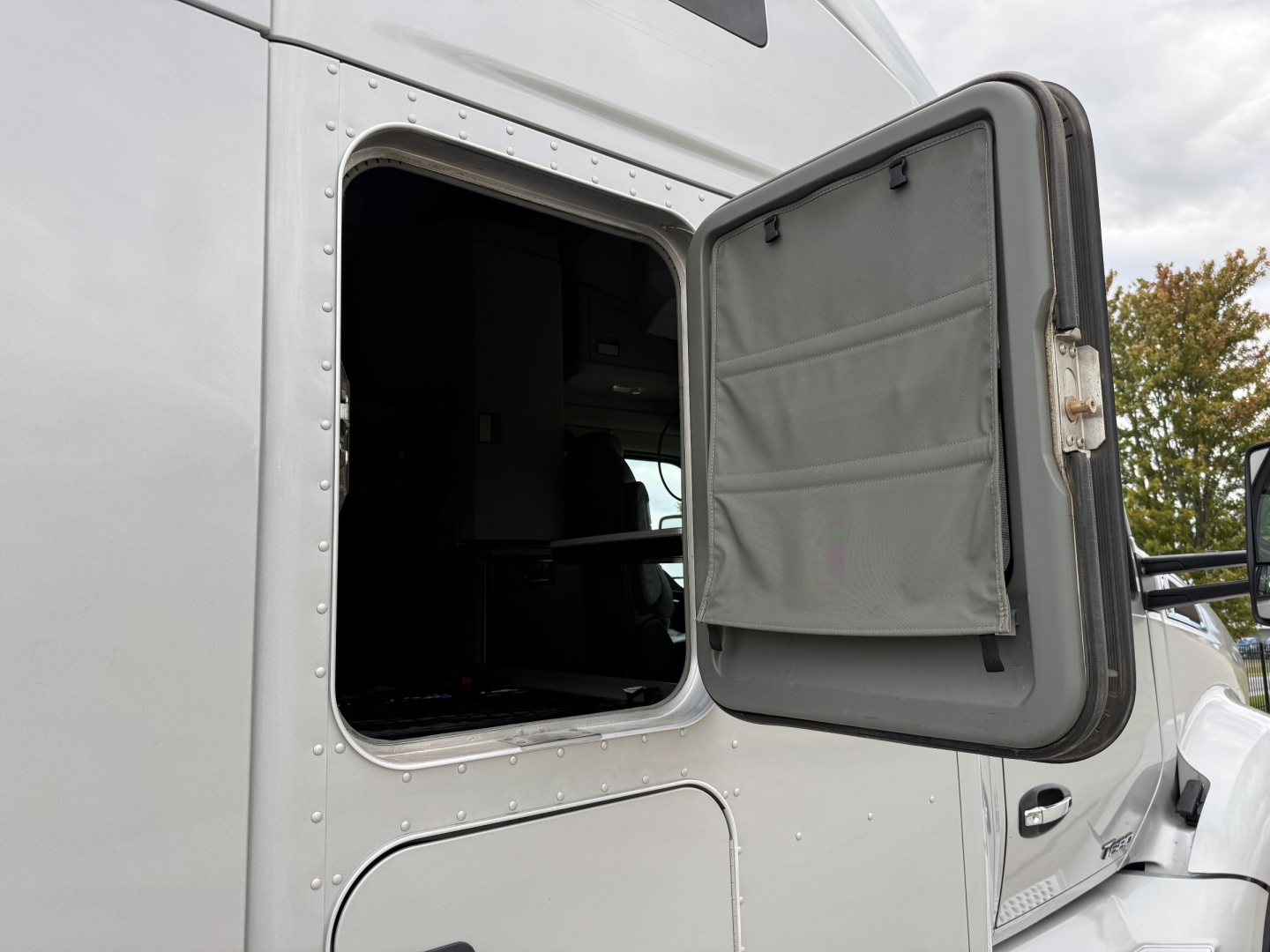 Kenworth T680 sleeper-cab tractor exterior with open door and empty sleeper window opening.
