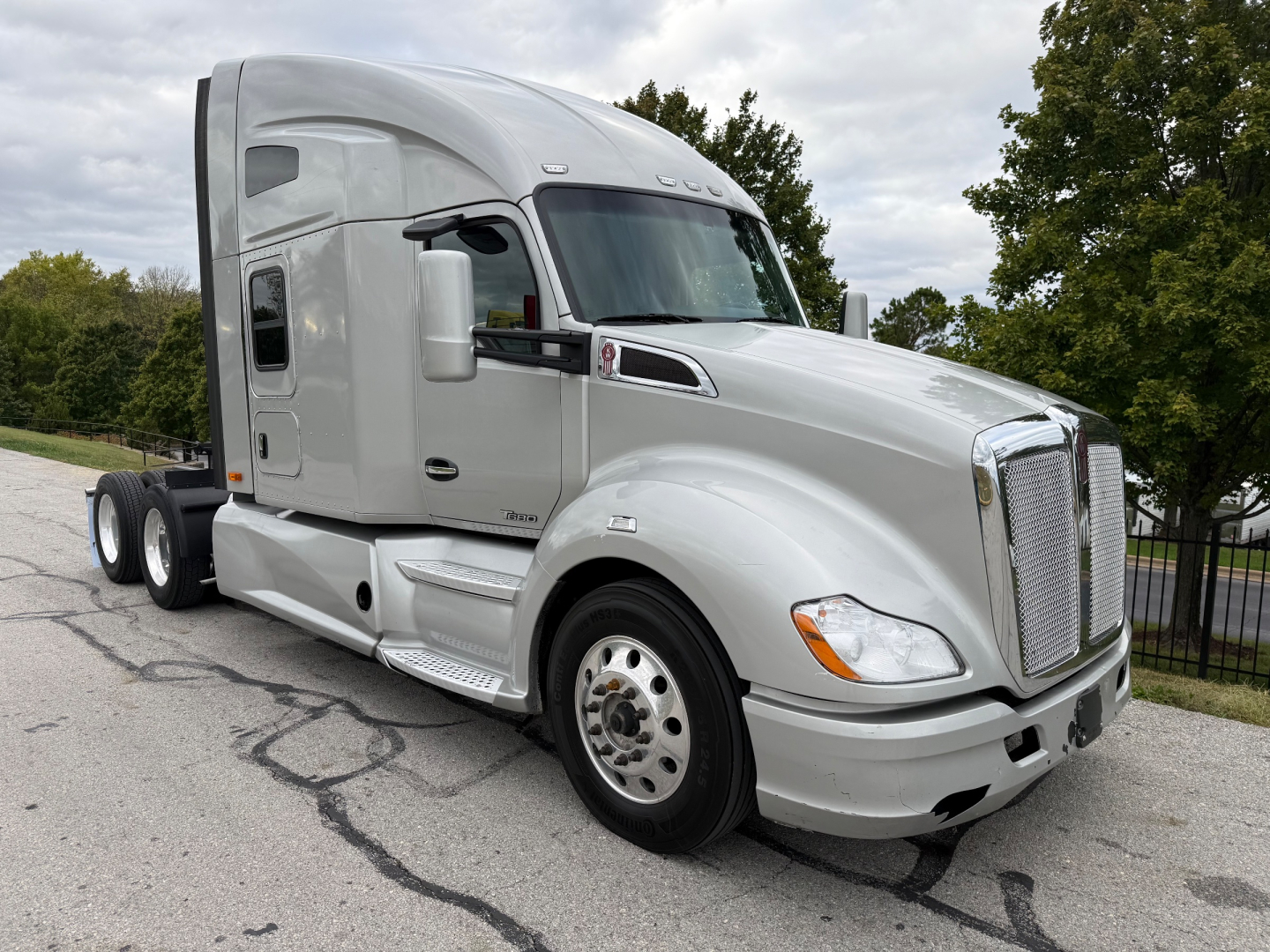 Kenworth T680 tractor cab in light gray, front-right view showing sleeper cab, chrome grille, dual rear axles, Pennsylvanian highway.