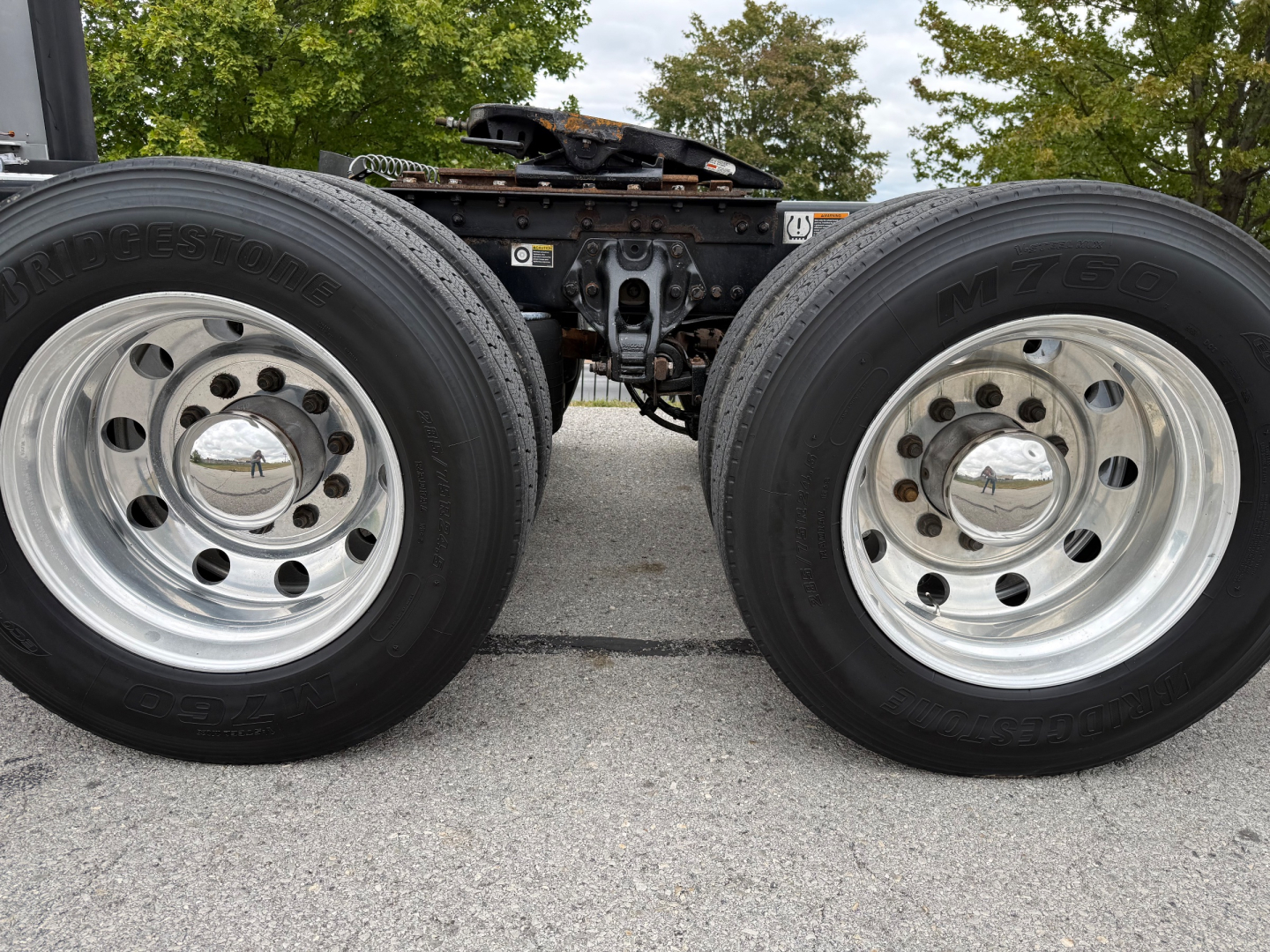 Twin Kenworth wheel ends and fifth wheel assembly visible, with front dual rear wheels and chrome rims.
