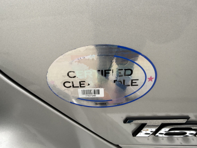 Kenworth T680 badge with a certified clean title sticker on silver truck body.