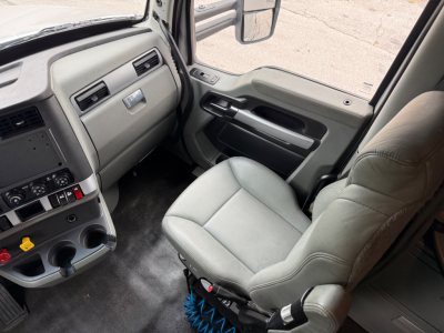 Kenworth T680 truck interior cabin view from passenger side showing dashboard, steering wheel, gear selector, and gray upholstery.