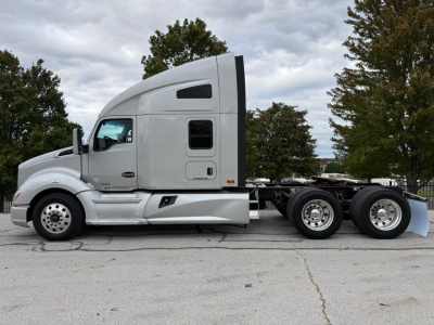 Kenworth T680 tractor side view showing sleeper cab and dual rear axles with chrome wheels and white paint.