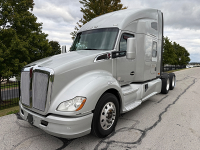 Kenworth T680 tractor cab side view with silver exterior and sleeper cabin, front grille, headlights, and wheel axles visible.