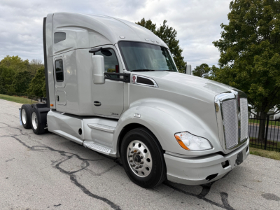 Kenworth T680 tractor in light gray, front three-quarter view showing sleeper cab and aerodynamic mirrors; no visible text on components.