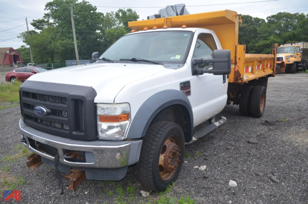 Ford F-550 dump truck with white cab and yellow dump bed, front view showing dual rear dump body and side mirrors.