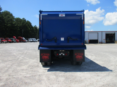 Dump truck rear showing dump bed, taillights, and mud flaps with logos.