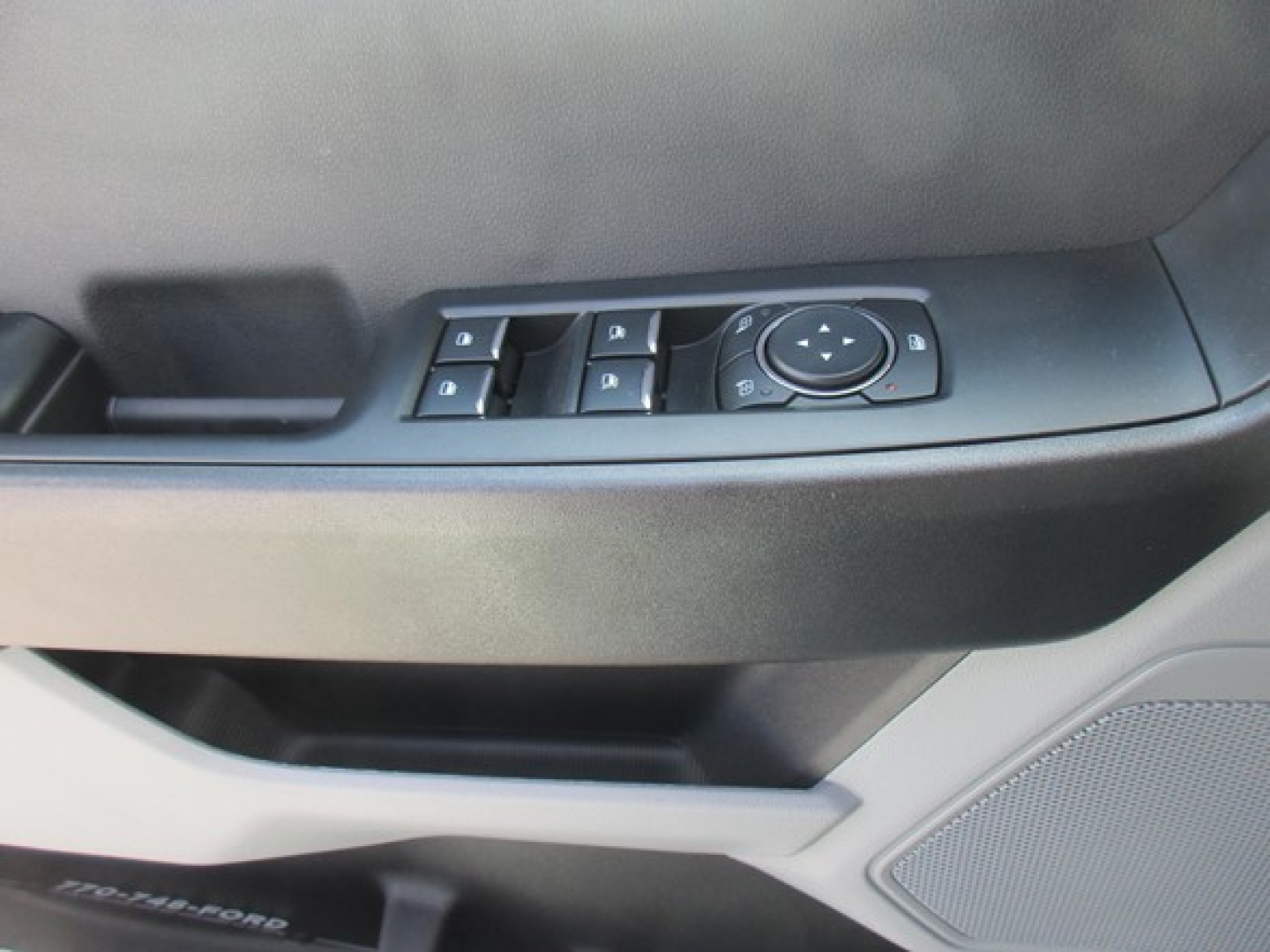 Ford F-Series truck interior door panel showing window/mirror controls and speaker grille.