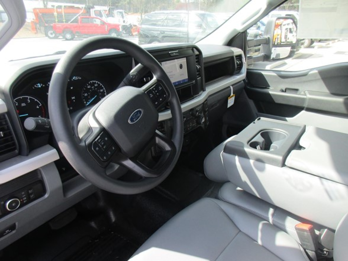 Ford F-350 interior showing steering wheel, dash gauges, center touchscreen, and front passenger seat area.