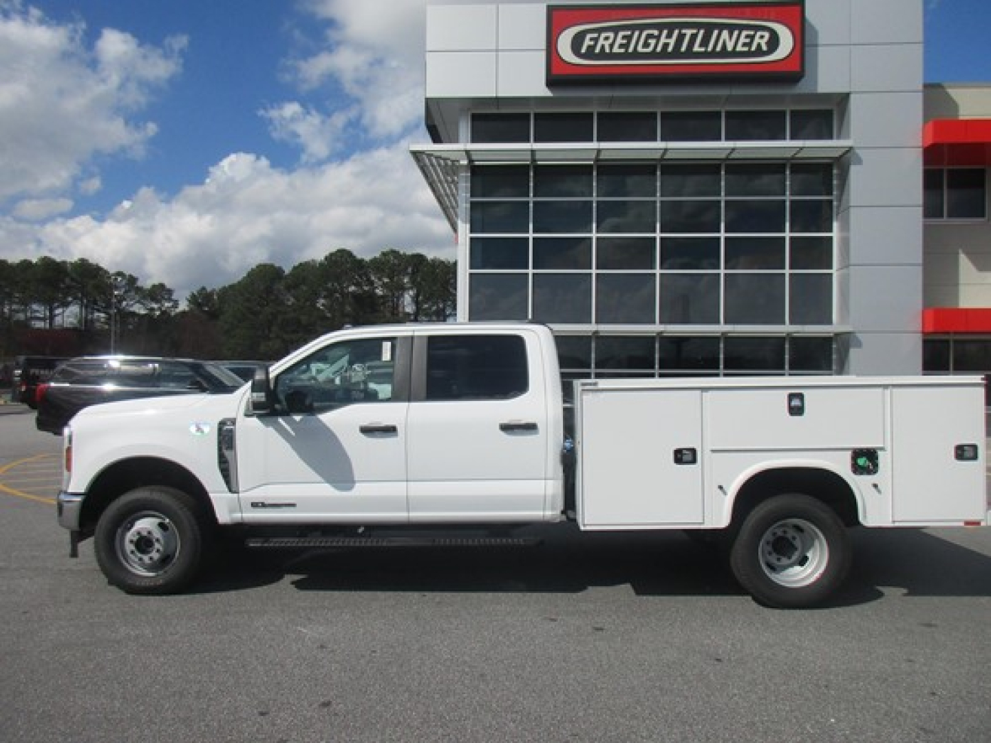 Ford F-350 service/utility truck in front of dealership with utility bed panels and dual rear wheels.