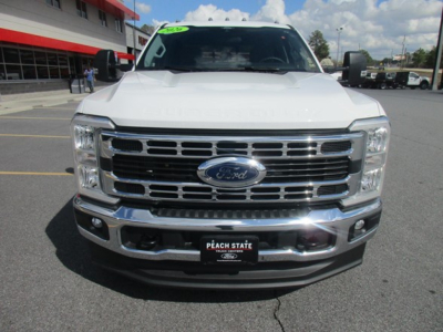 Front view of a white 2026 Ford F-350 truck showing Ford emblem grille, bumper, and headlights in dealership lot.