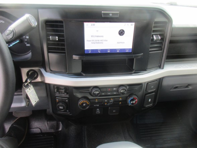 Ford F-350 cab interior showing center touchscreen display, climate controls, and steering wheel; dashboard with gear selector and key in ignition.