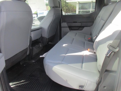 Truck interior rear seating area with light gray fabric seats, three seat belts, and rear door panel visible.