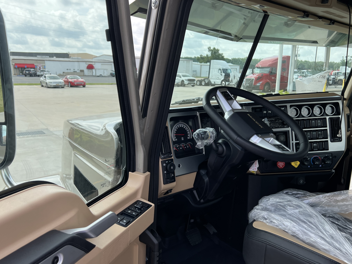 cab interior of a 2027 Mack PI64T truck showing steering wheel, instrument cluster, and dashboard controls with protective plastic on seat