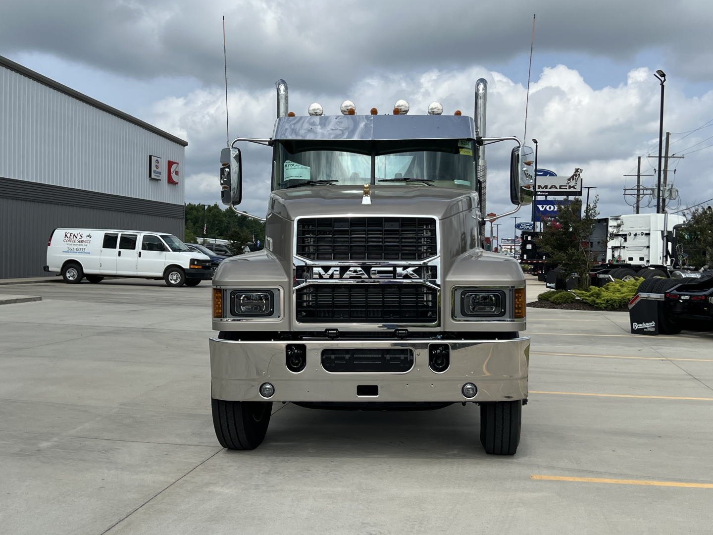 Front view of a new 2027 Mack PI64T conventional daycab truck showing large grille with MACk logo, chrome bumper, and dual headlights.