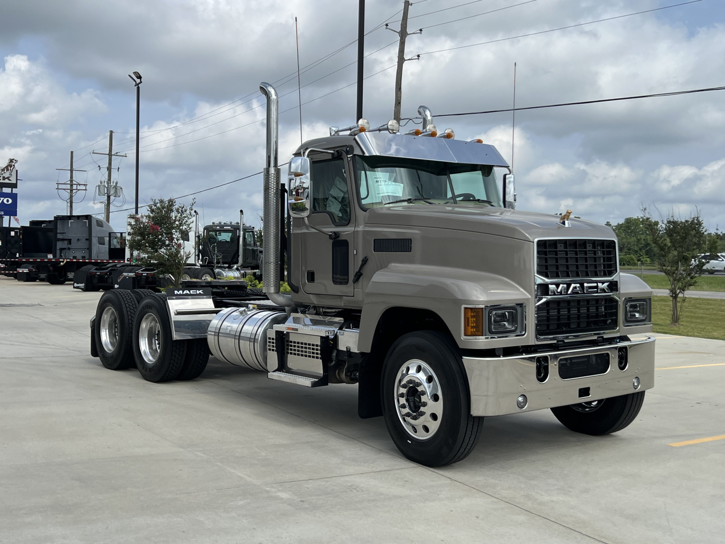 Mack PI64T truck shown from front-left angle with tan/gray exterior and chrome exhaust stacks.