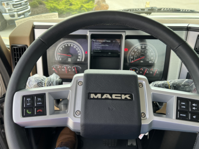 Mack PI64T truck interior showing steering wheel with MACK logo and instrument cluster with gauges and central display.