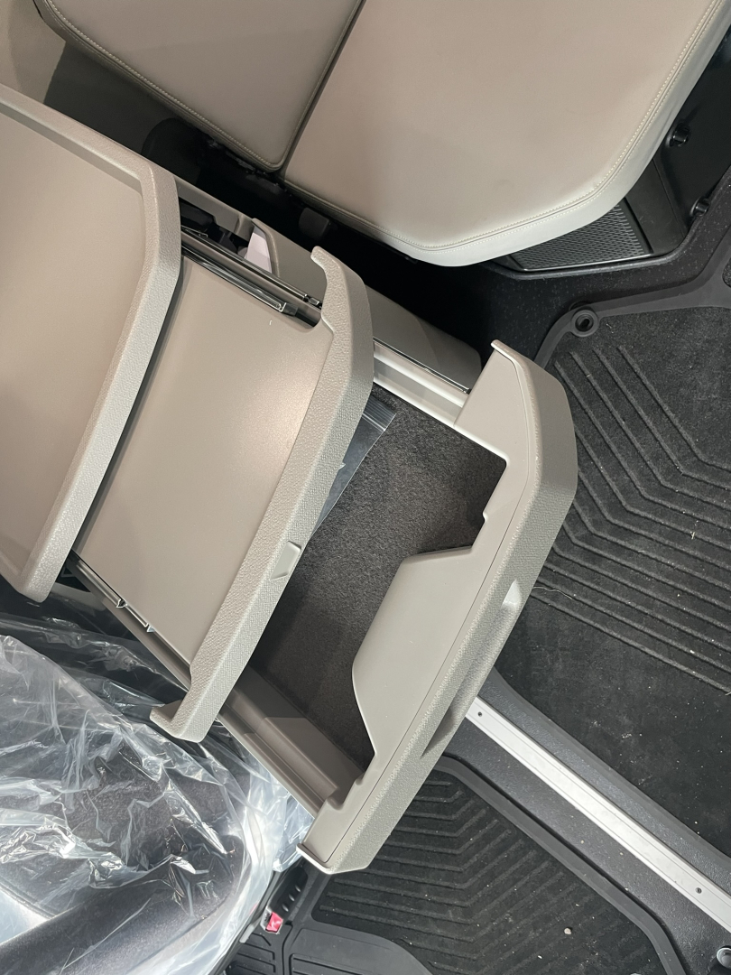 Volvo VNL64T860 cab interior showing center storage tray and open drawers under front seat area.