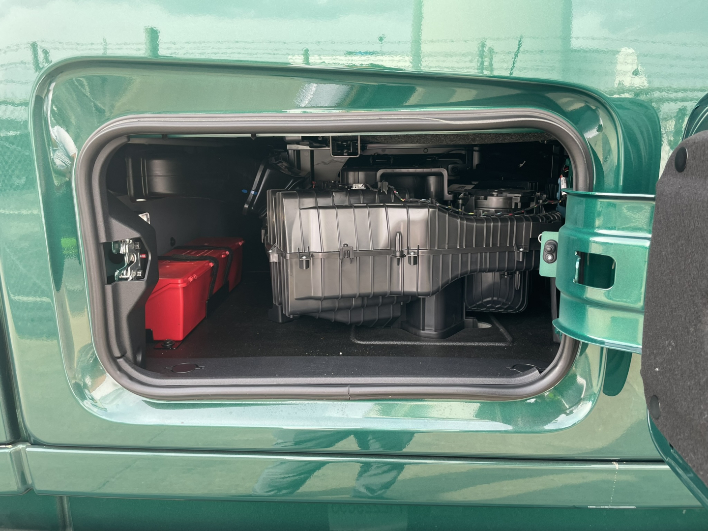 Volvo VNL64T860 truck engine bay showing front compartment with a silver engine component and a red battery pack visible in storage area.