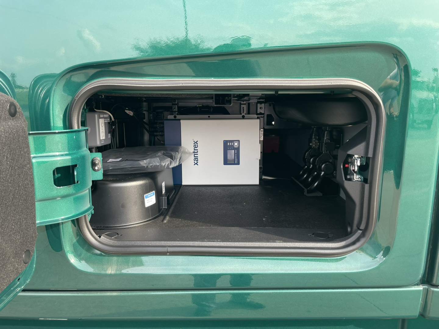 Volvo VNL64T860 engine bay storage compartment showing auxiliary power unit and equipment in rear cabinet.