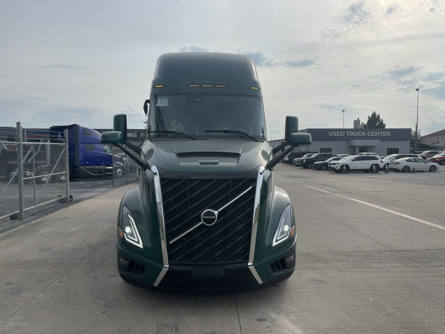 Front view of a new Volvo VNL64T860 truck with prominent grille and Volvo badge, daytime lighting in a dealership lot.