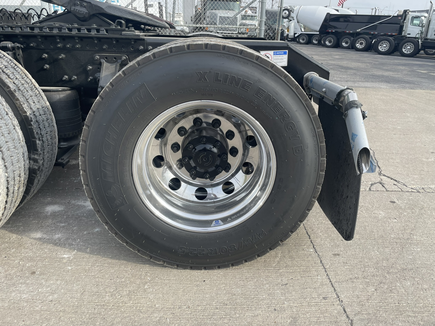 Volvo VNL64T860 truck rear wheel assembly with Mobil 11R-22.5 tire and polished metal rim; fender and undercarriage components visible.